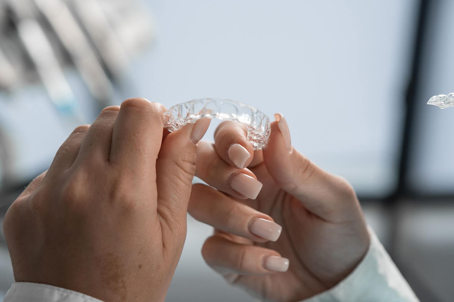 Close-up of a patient’s hands holding a set of clear aligners, showing how custom trays are used in modern orthodontic treatment for straighter teeth.