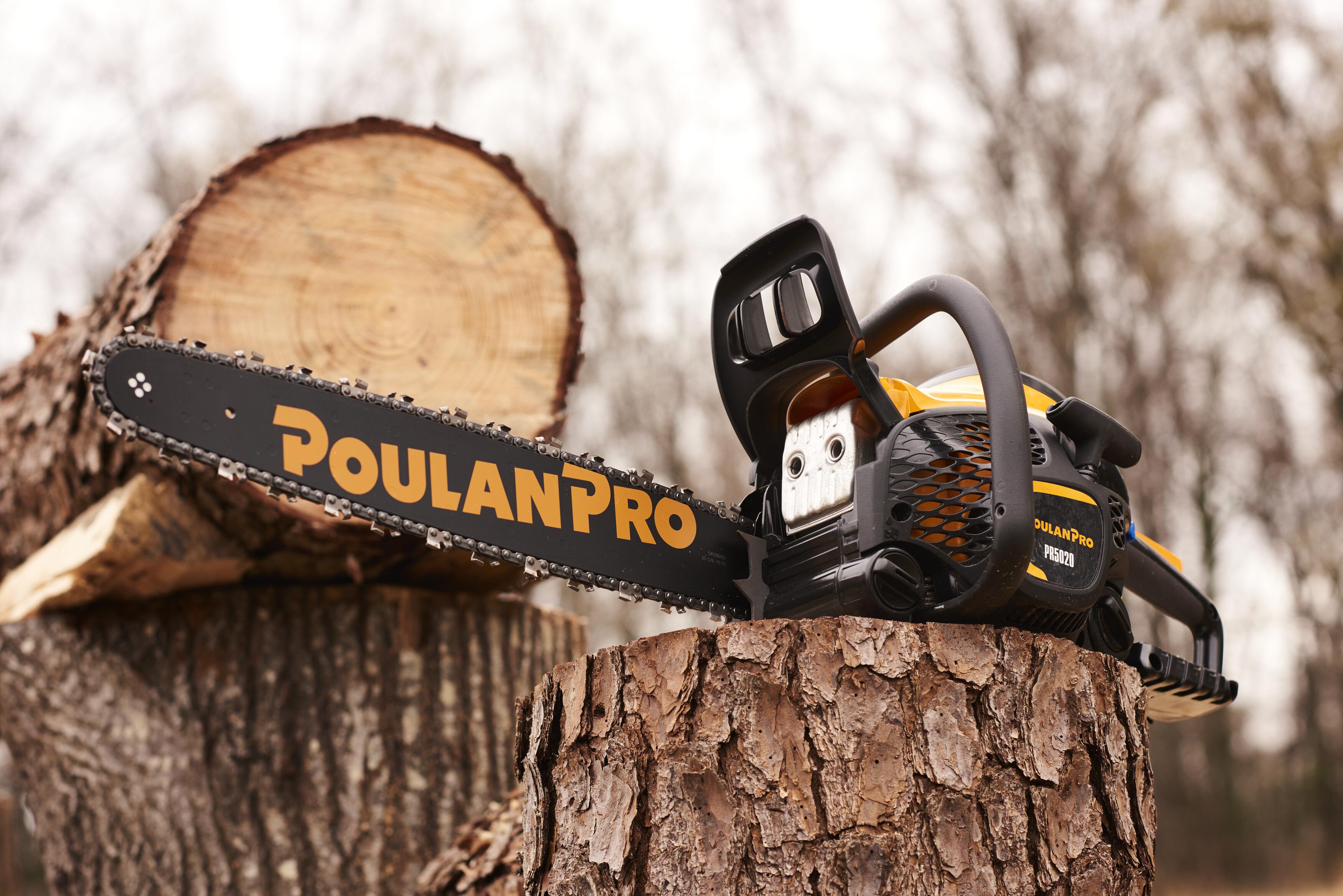 Close-up of a Poulan Pro chainsaw resting on a tree stump with a large log in a blurred forest background.