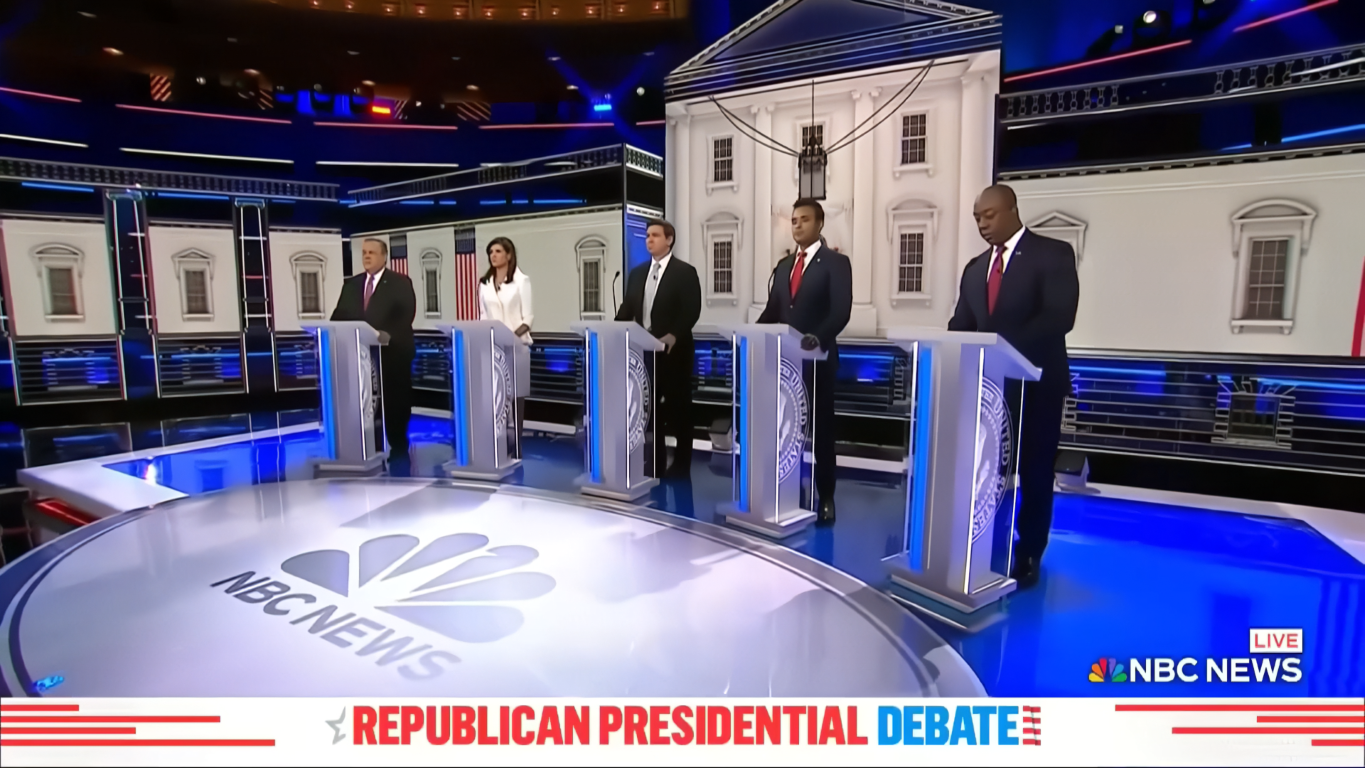 Five Republican presidential candidates standing behind podiums on an NBC News debate stage with White House backdrop.