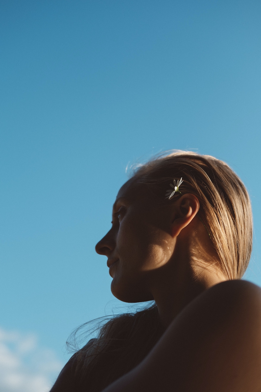 woman looking to the left shadowed by sun with blue sky in the background