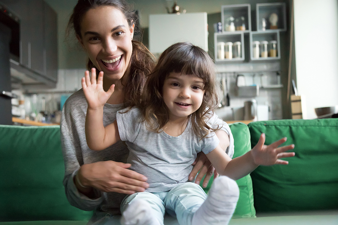 Mom sitting with a child in her lap and they are both smiling. 