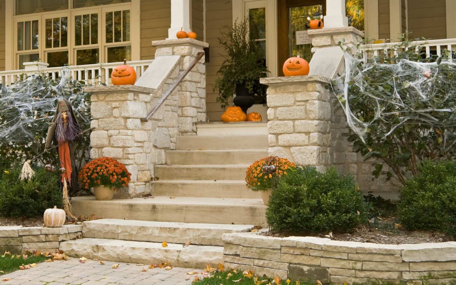 The front walkway of a home decorated for Halloween with pumpkins.