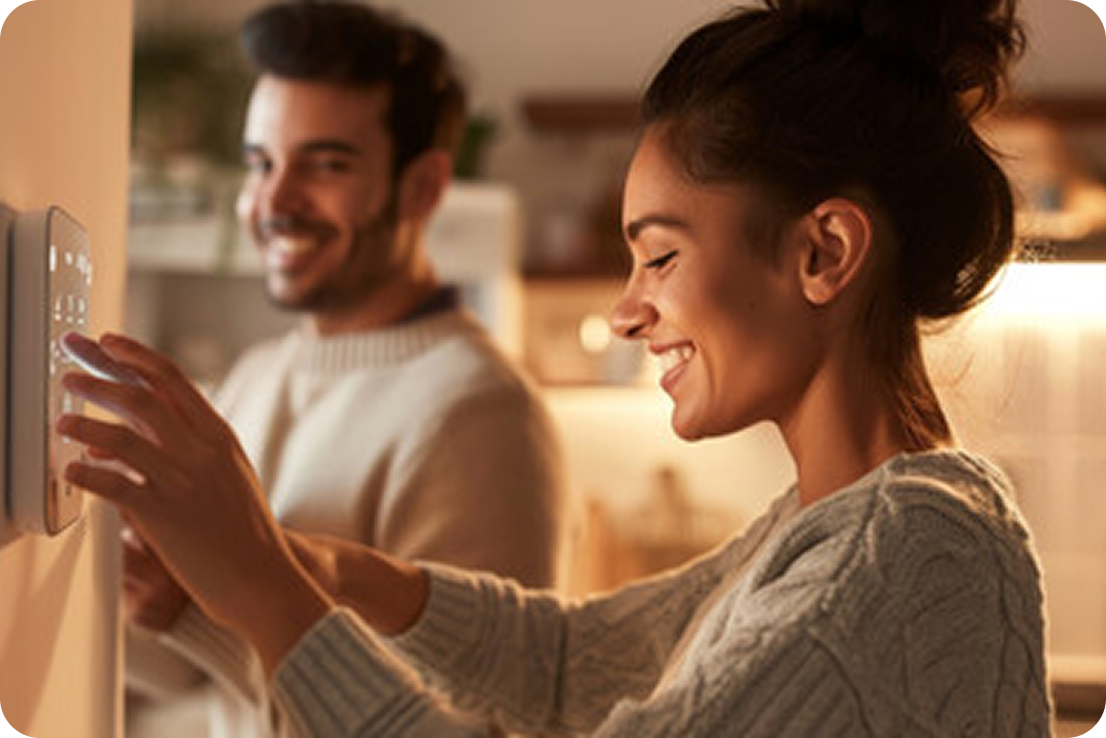 Couple standing in the kitchen using a security system. 