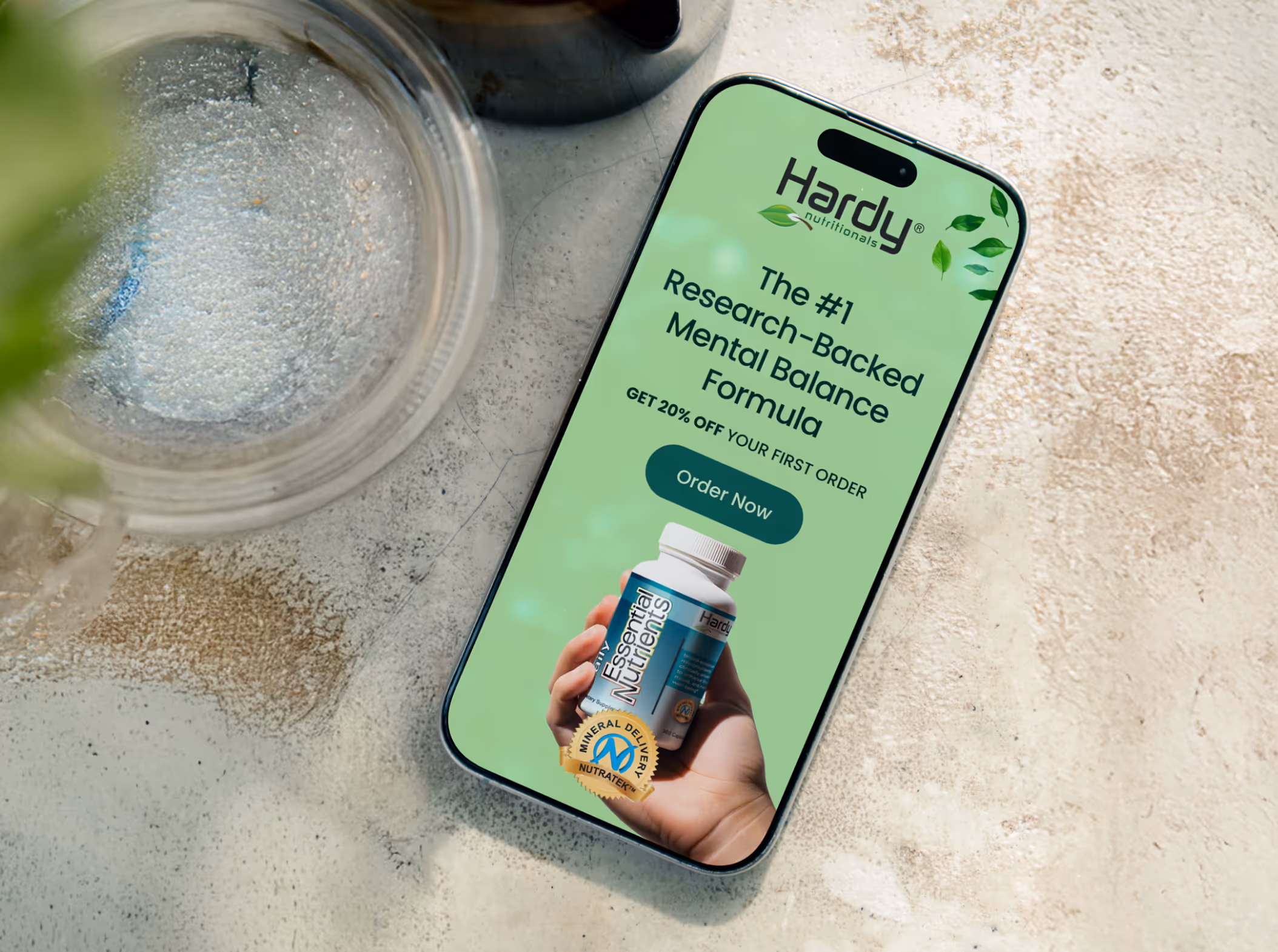 Smartphone on a beige surface displaying Hardy Nutritionals ad for a mental balance formula with 20% off first order and an Essential Nutrients supplement bottle.