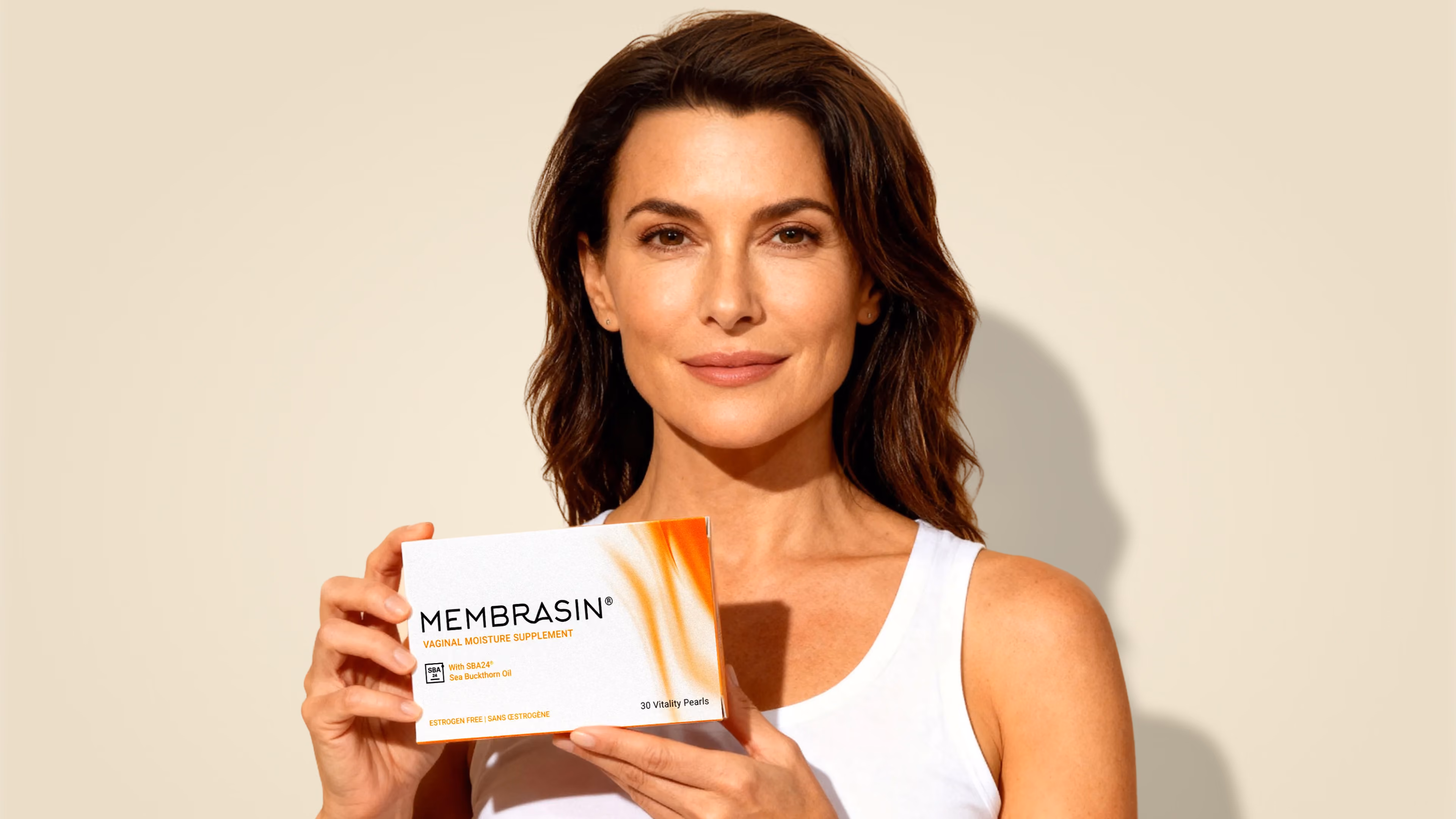 Woman holding an EllaNu product box against a warm cream background.