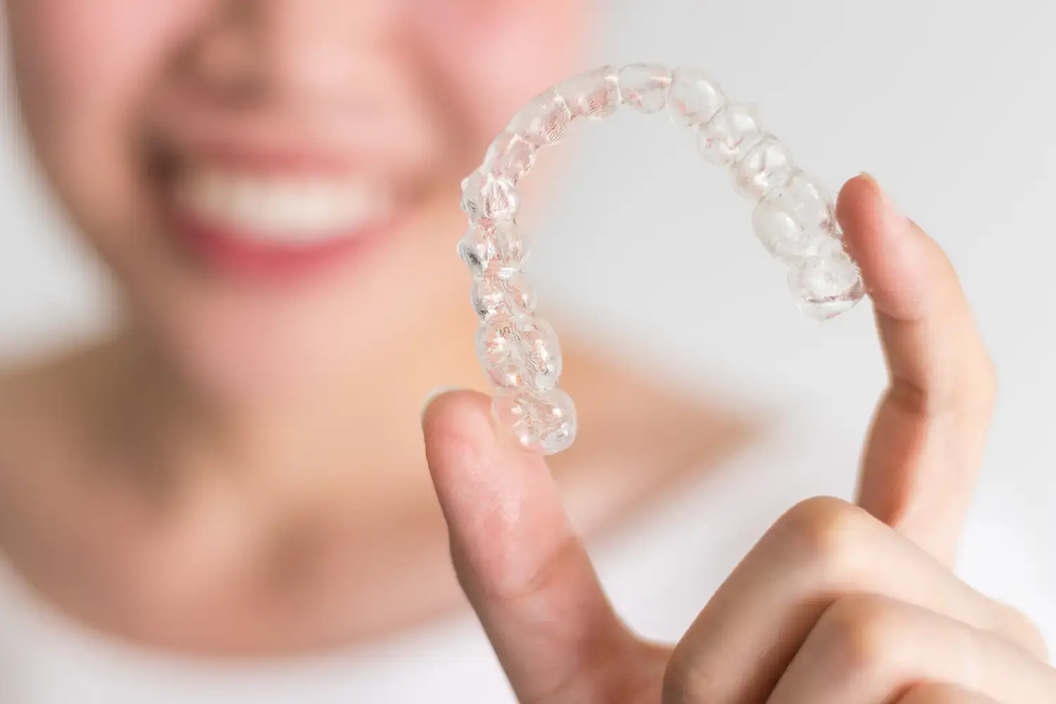 A smiling person holding an Invisalign tray