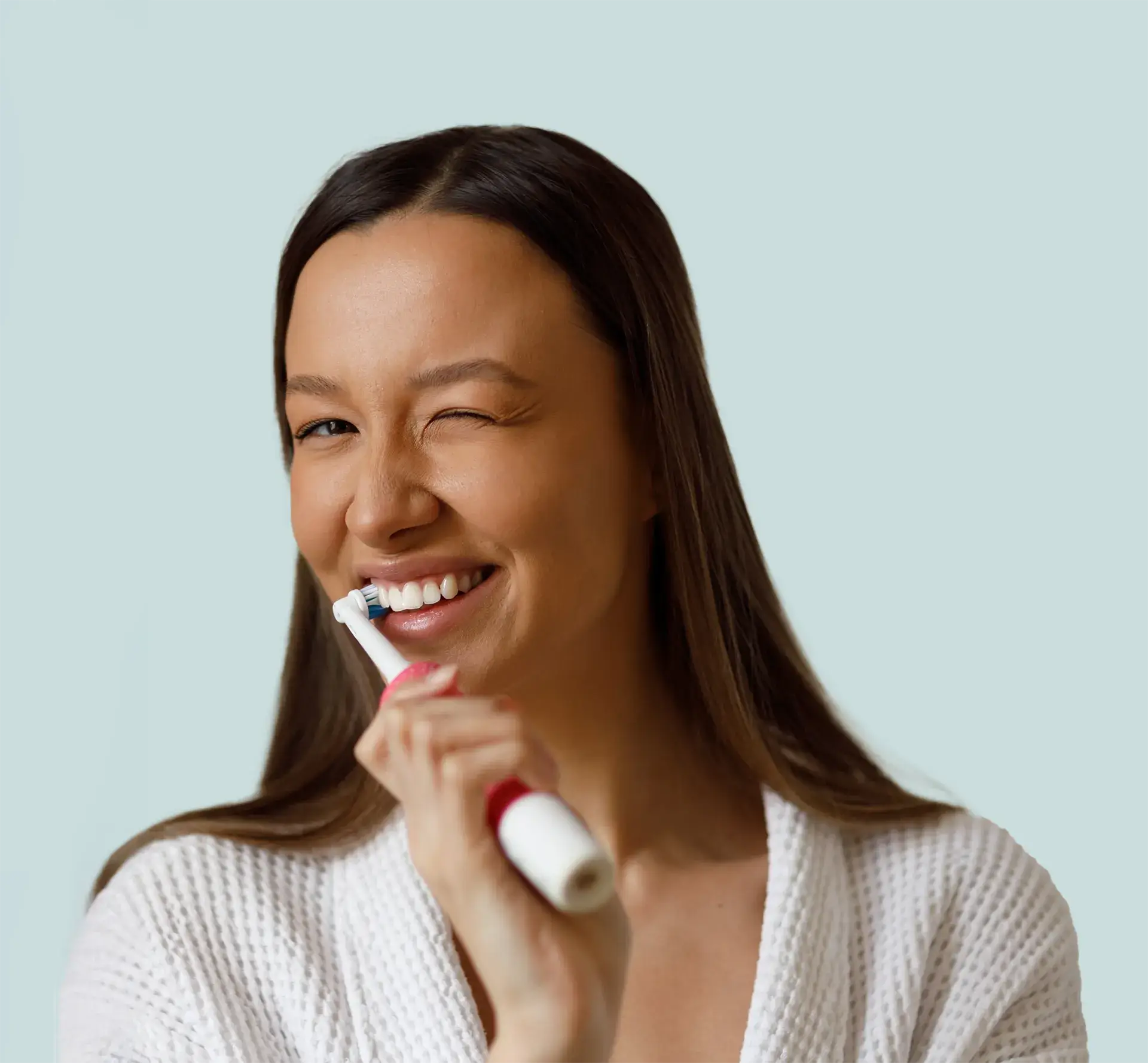 A woman brushing her teeth and winking