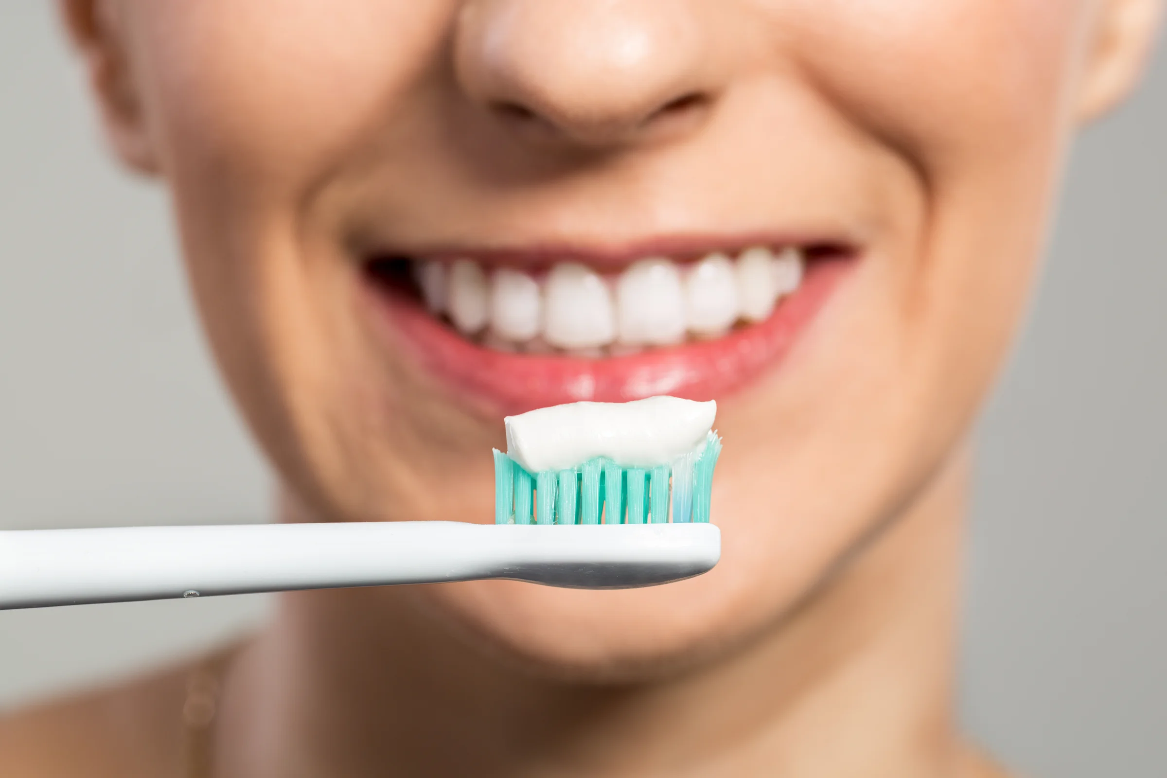 A close up photo of a smiling person with a toothbrush