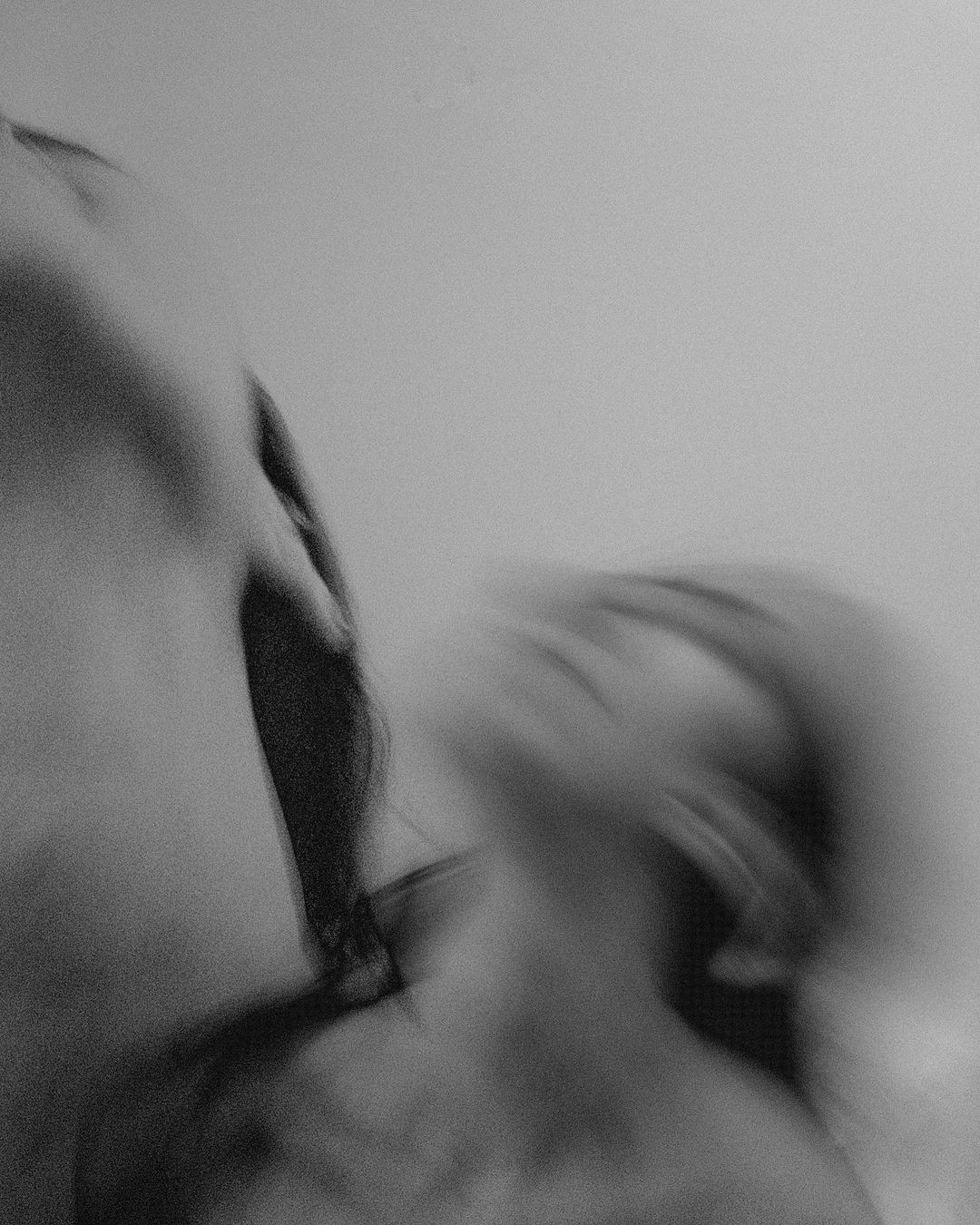 Portrait artistique flou en noir et blanc montrant un couple rapproché avec des mouvements de tête flous.