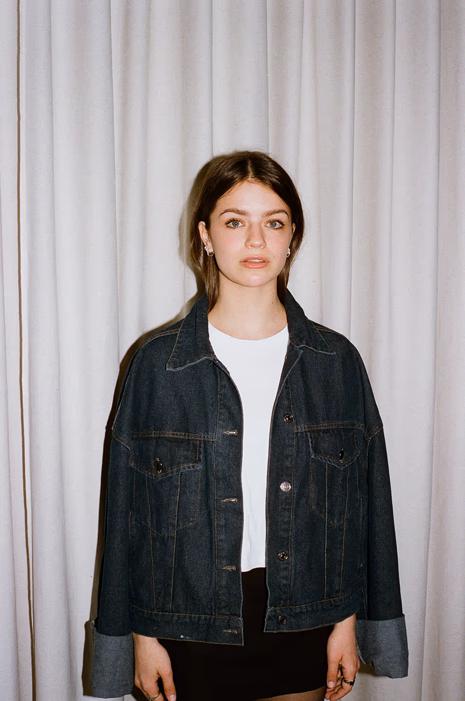 Ariane Brunet est une comédienne avec les cheveux plats et un chandail blanc qui porte une veste en jeans.