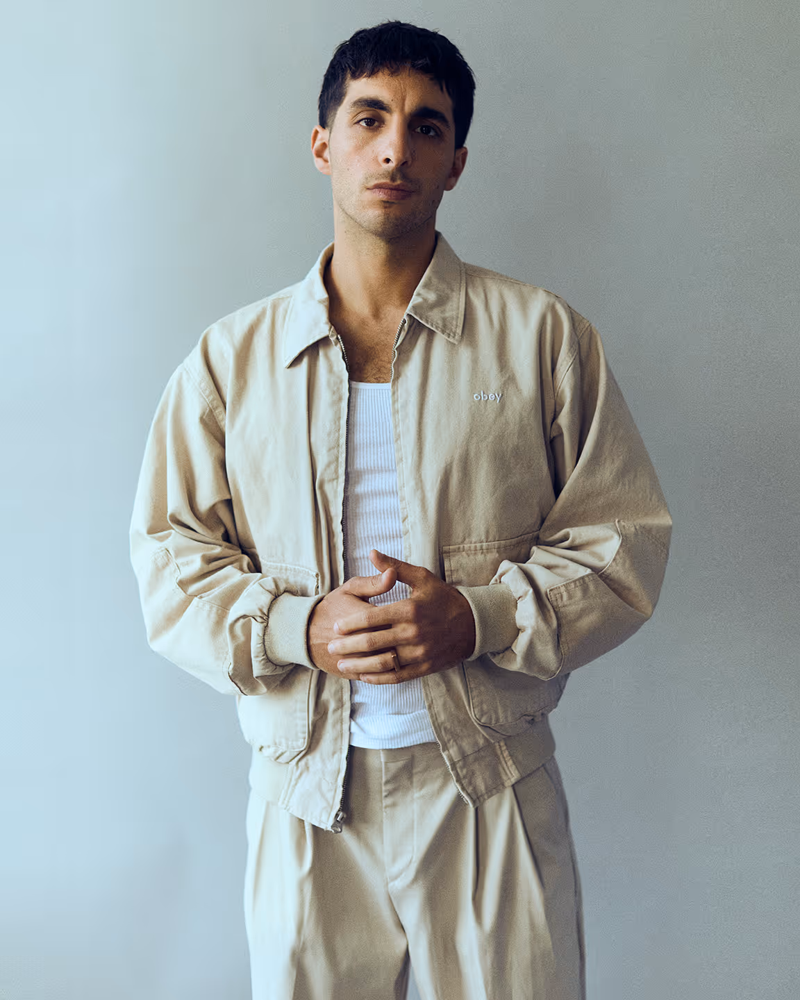 Mike Clay porte un tracksuit beige qui ressemble à Adidas. 