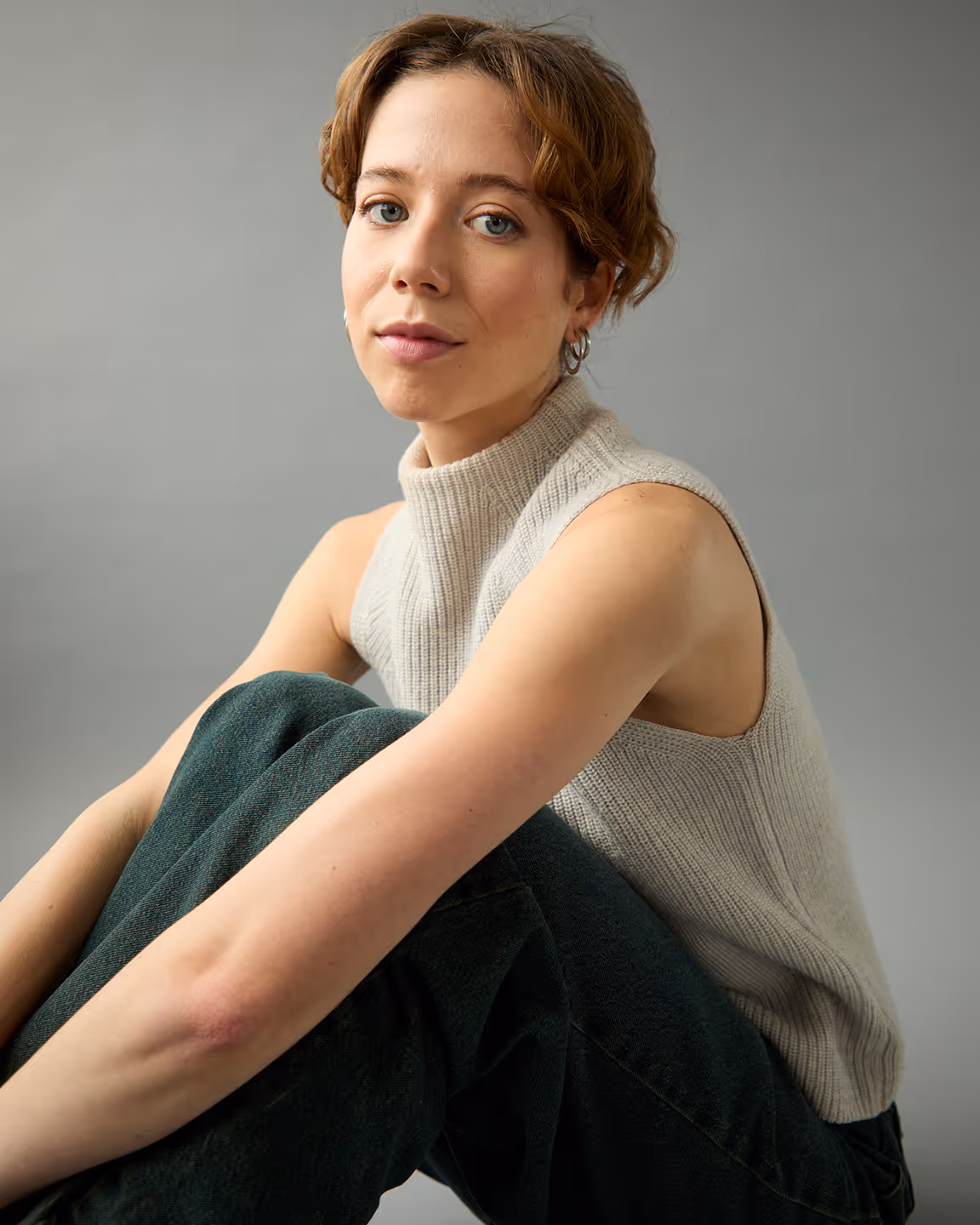 Margot Blondin est une comédienne avec les jambes croisées et un col roulé beige.