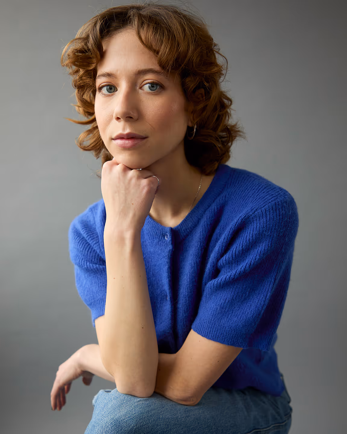 Margot Blondin est une actrice avec les cheveux bouclés et une laine bleue.