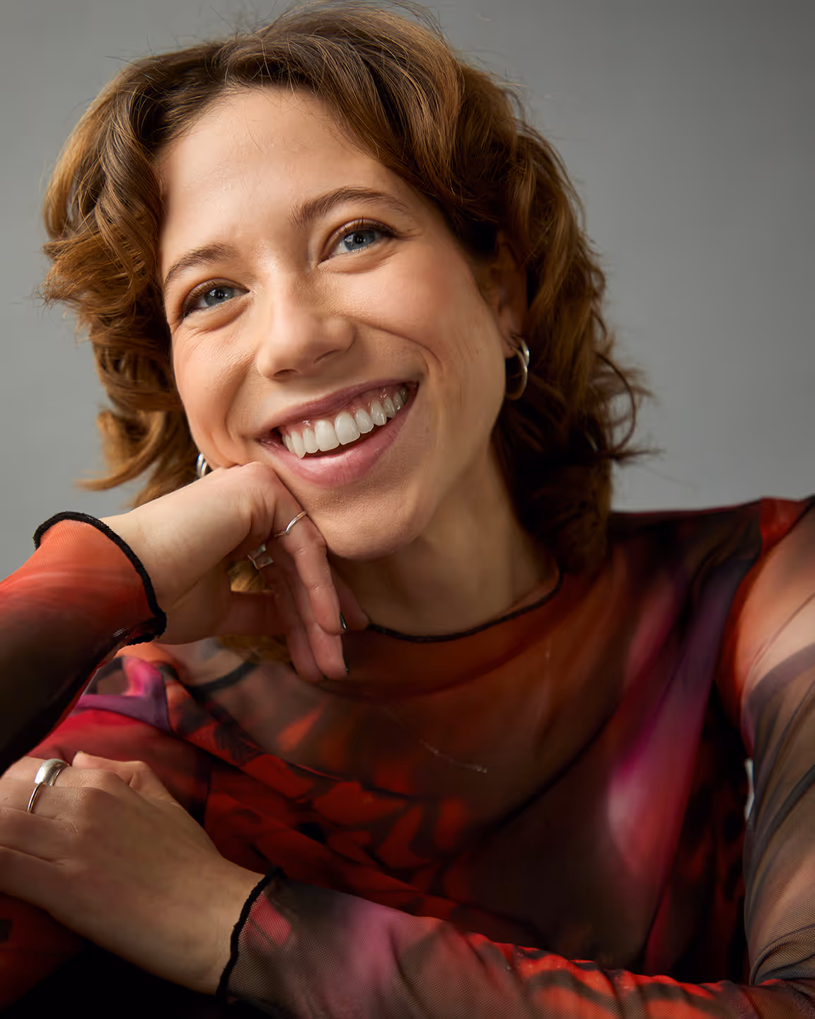 Margot Blondin souriante avec un chandail transparent rouge.