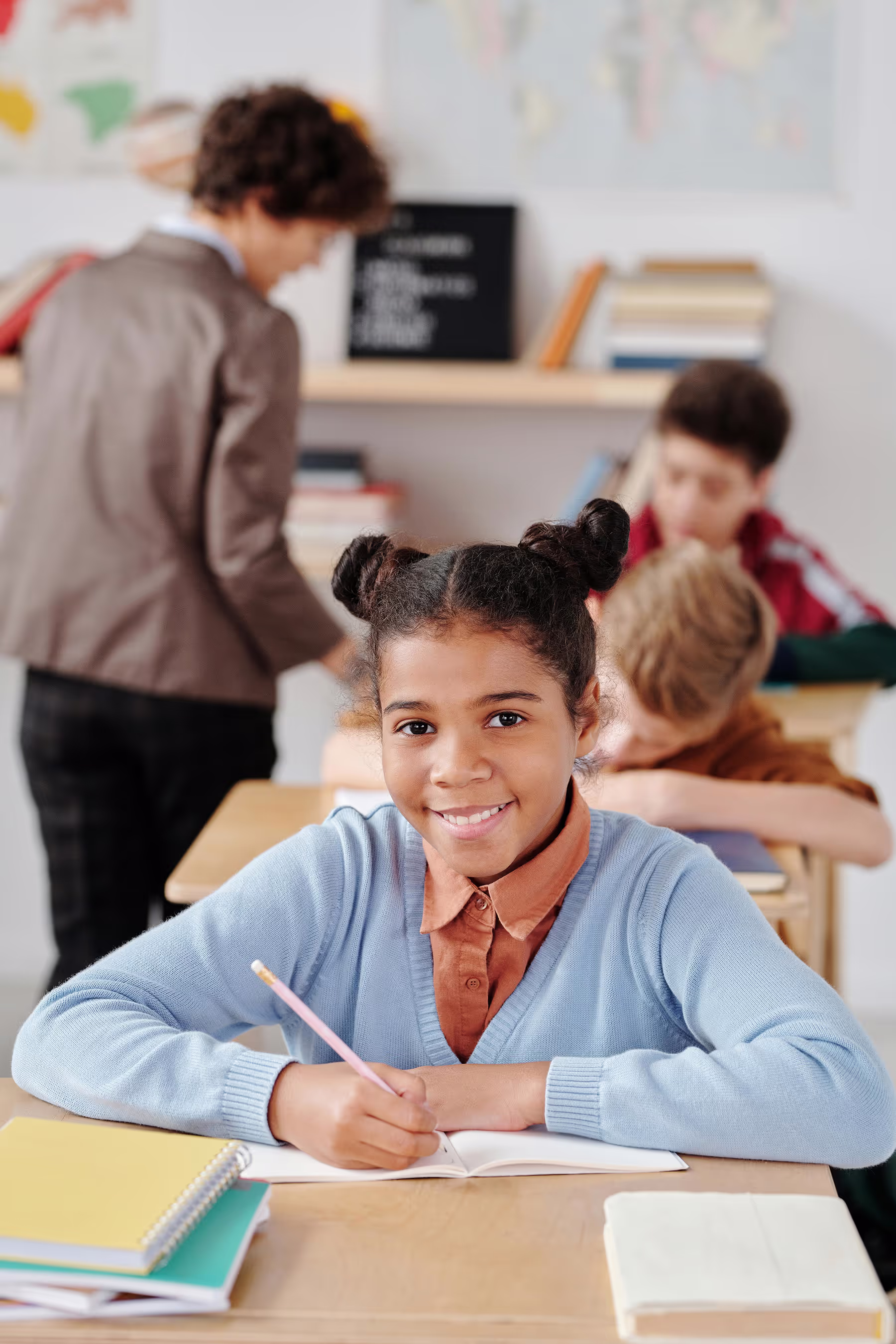 A happy schoolgirl sits at her desk, smiling with a sense of enthusiasm and positivity