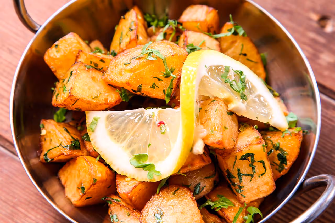 Batata Harra plate with baked potatoes pieces and lemon and hot spices