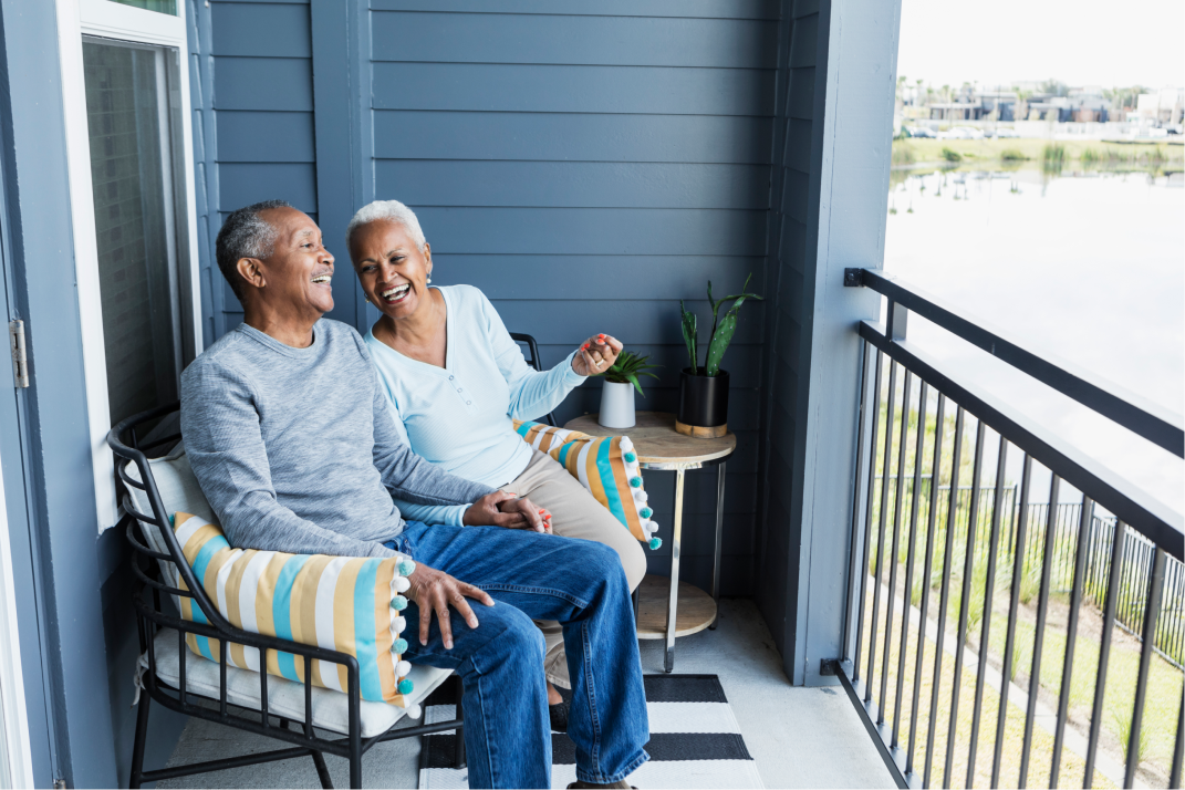 An older couple laughing on the front porch