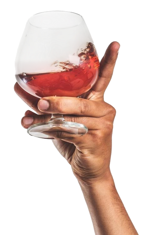 Hand hält ein Cognacglas mit rotbraunem Getränk, das leicht schwappt.