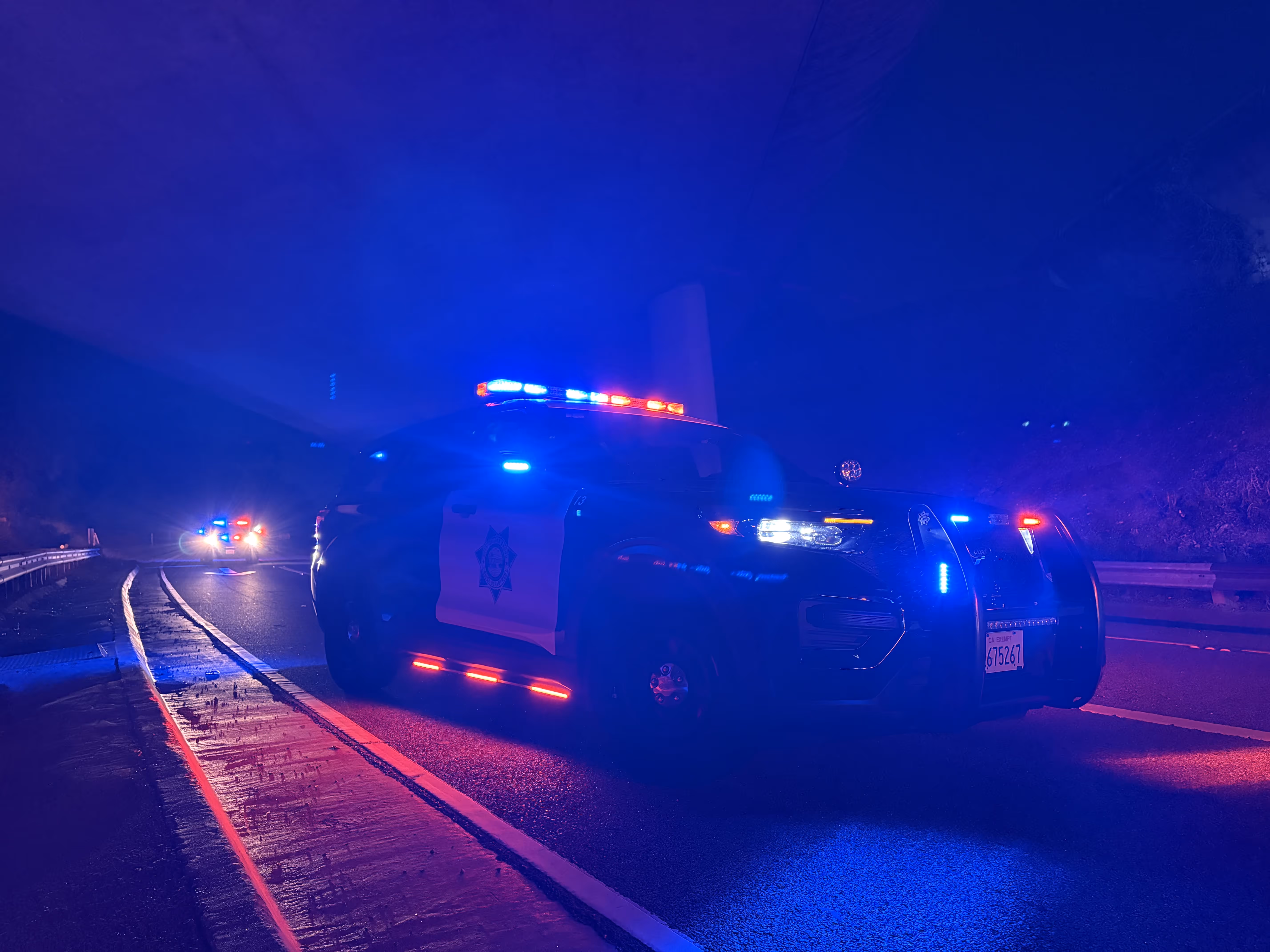 Parked police SUV with flashing red and blue lights on a dark road at night.