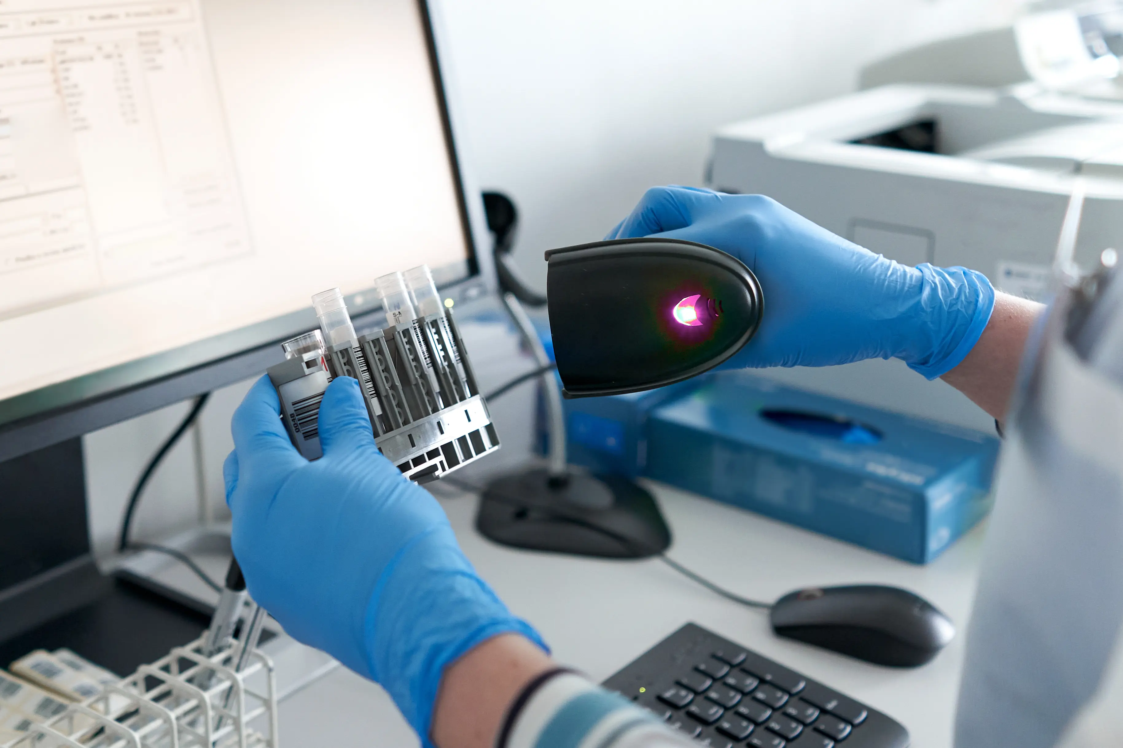 Laboratory sample tracking: scientist scanning barcoded tubes at a lab workstation.