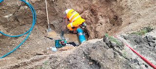 A person in a yellow vest working in a holeAI-generated content may be incorrect.