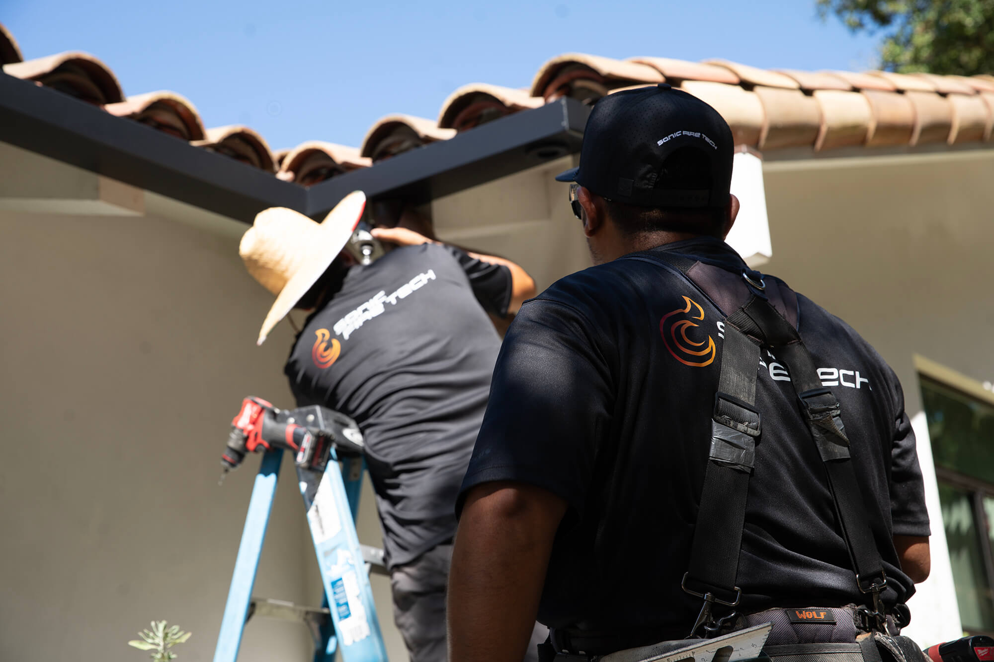 Installers installing Sonic Fire Defense system on a house