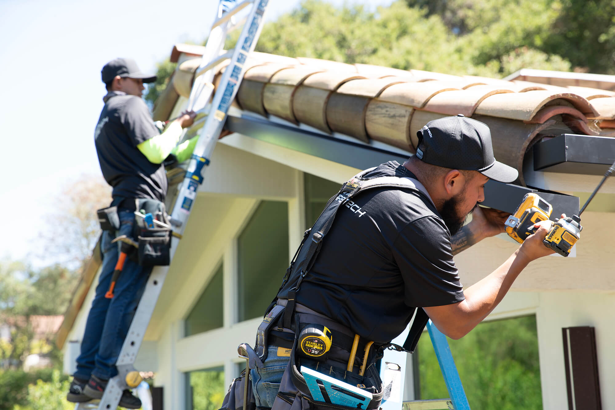 Installers installing Sonic Fire Defense system on a house