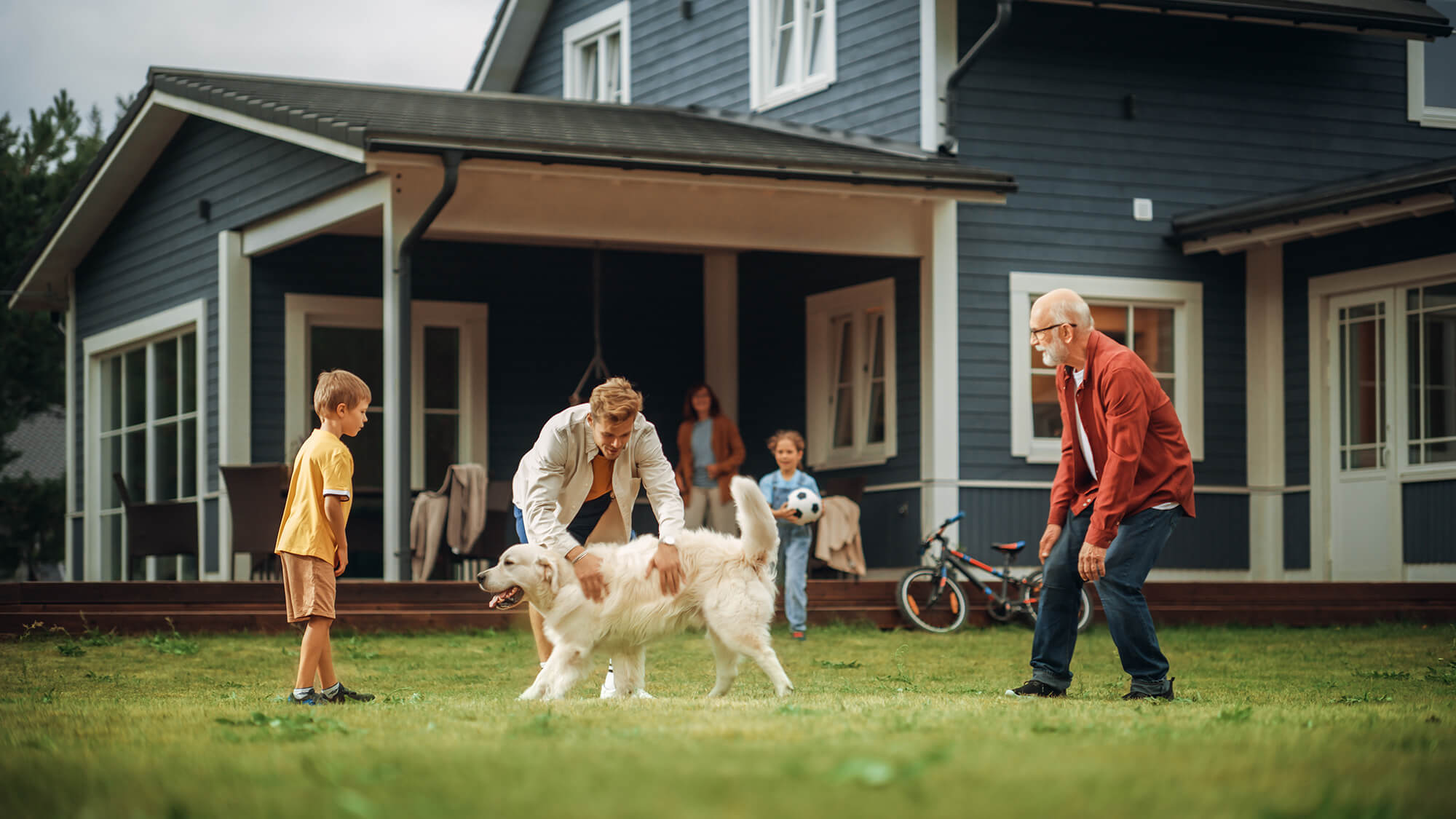 Family playing their dog in the front yard of home