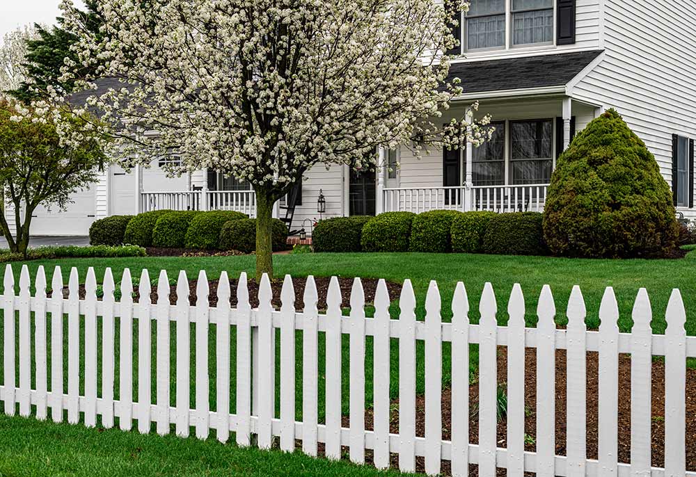 A white picket fence surrounds a house