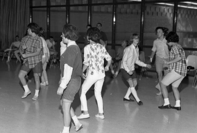 A sock hop happening in the rec center in black and white