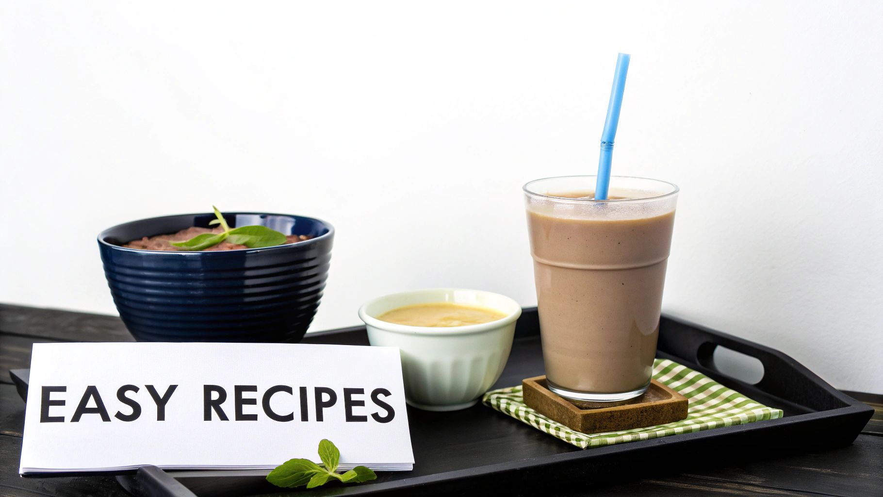 A black tray with a blue bowl of food, a healthy smoothie, and an 'EASY RECIPES' card.