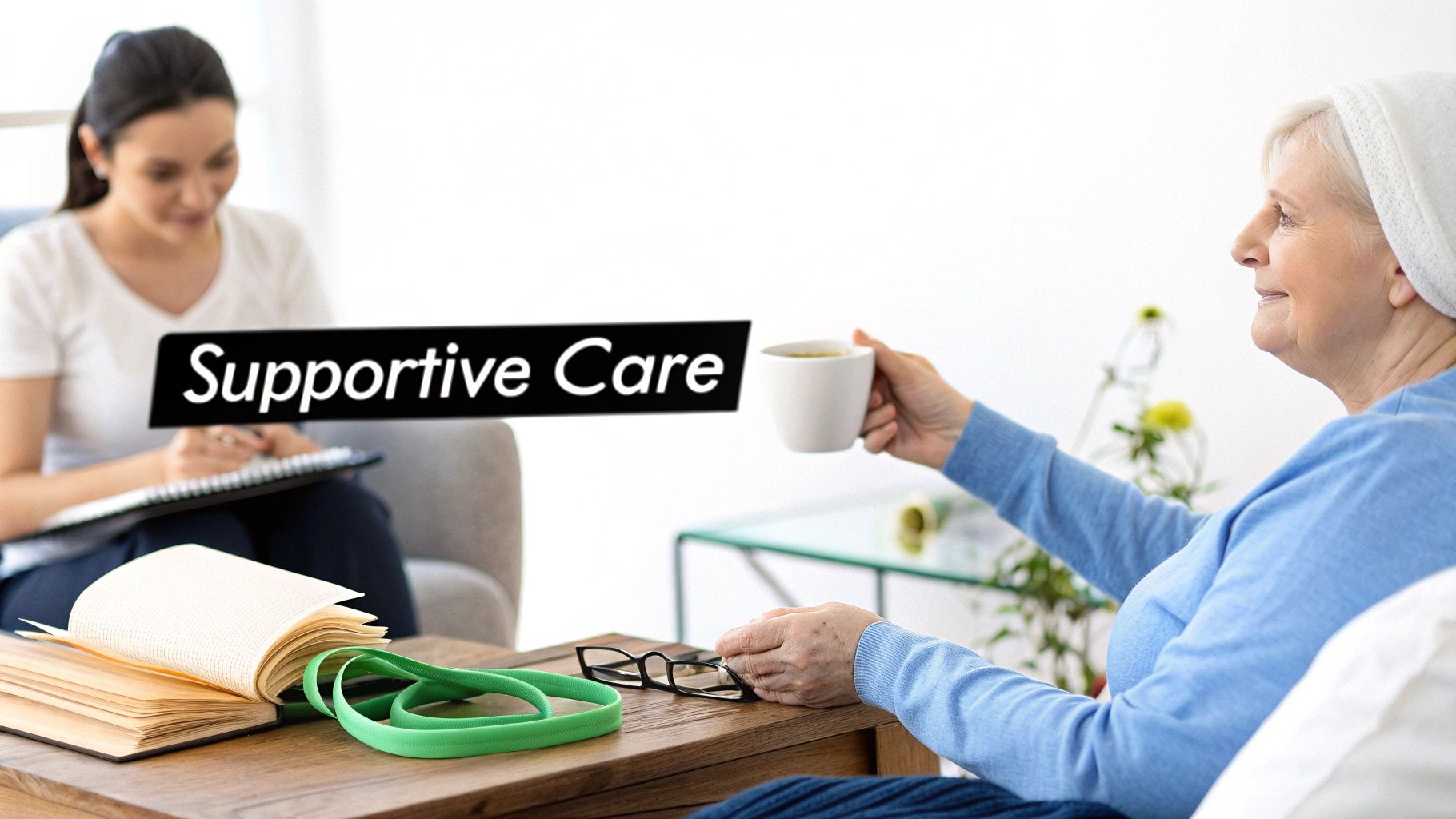 An older woman in a headscarf smiles, receiving supportive care from a younger woman during a consultation.