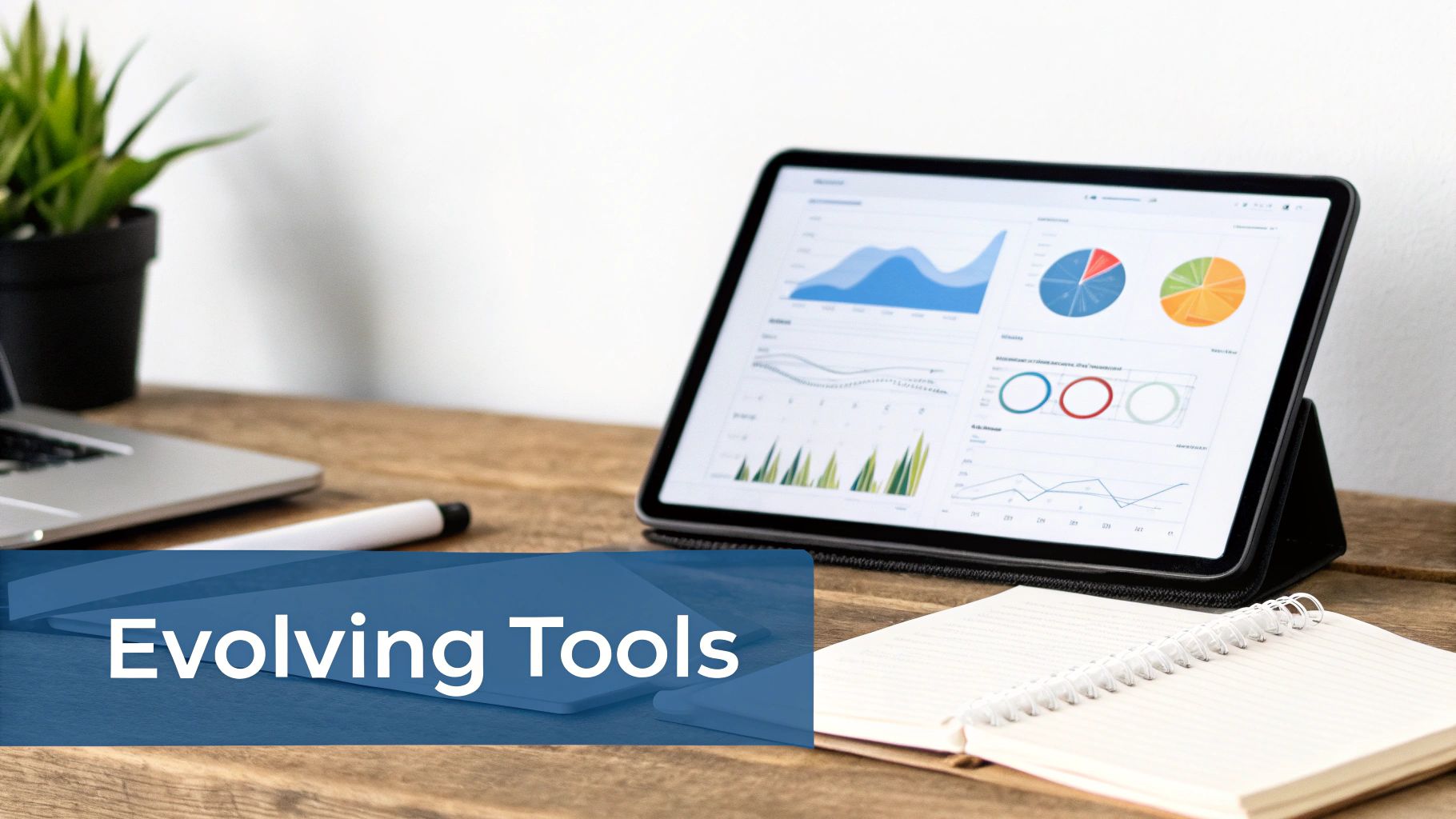 A desk setup with a tablet displaying charts, a laptop, plant, pen, and notebook. Text 'Evolving Tools'.