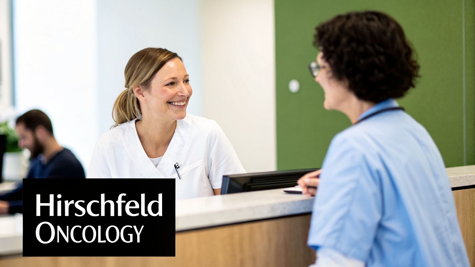 Two smiling medical professionals interacting at a modern oncology clinic reception desk.