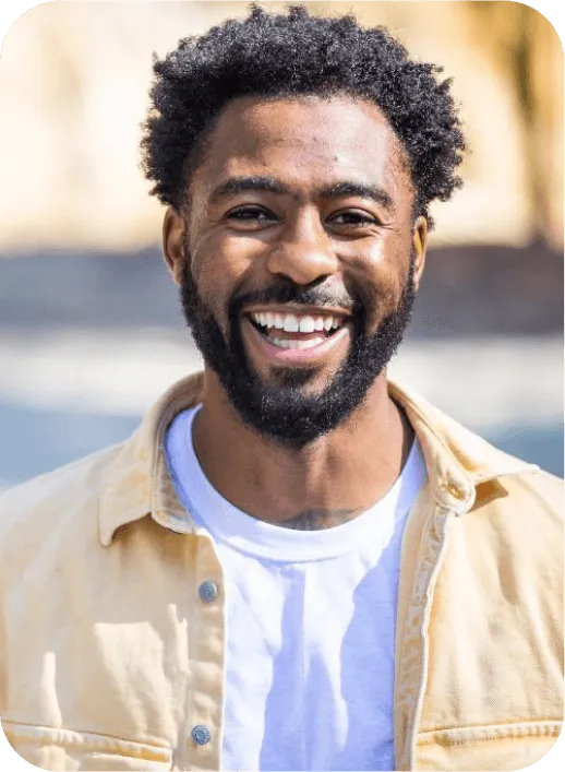 Person in a white shirt and beige jacket with curly hair.
