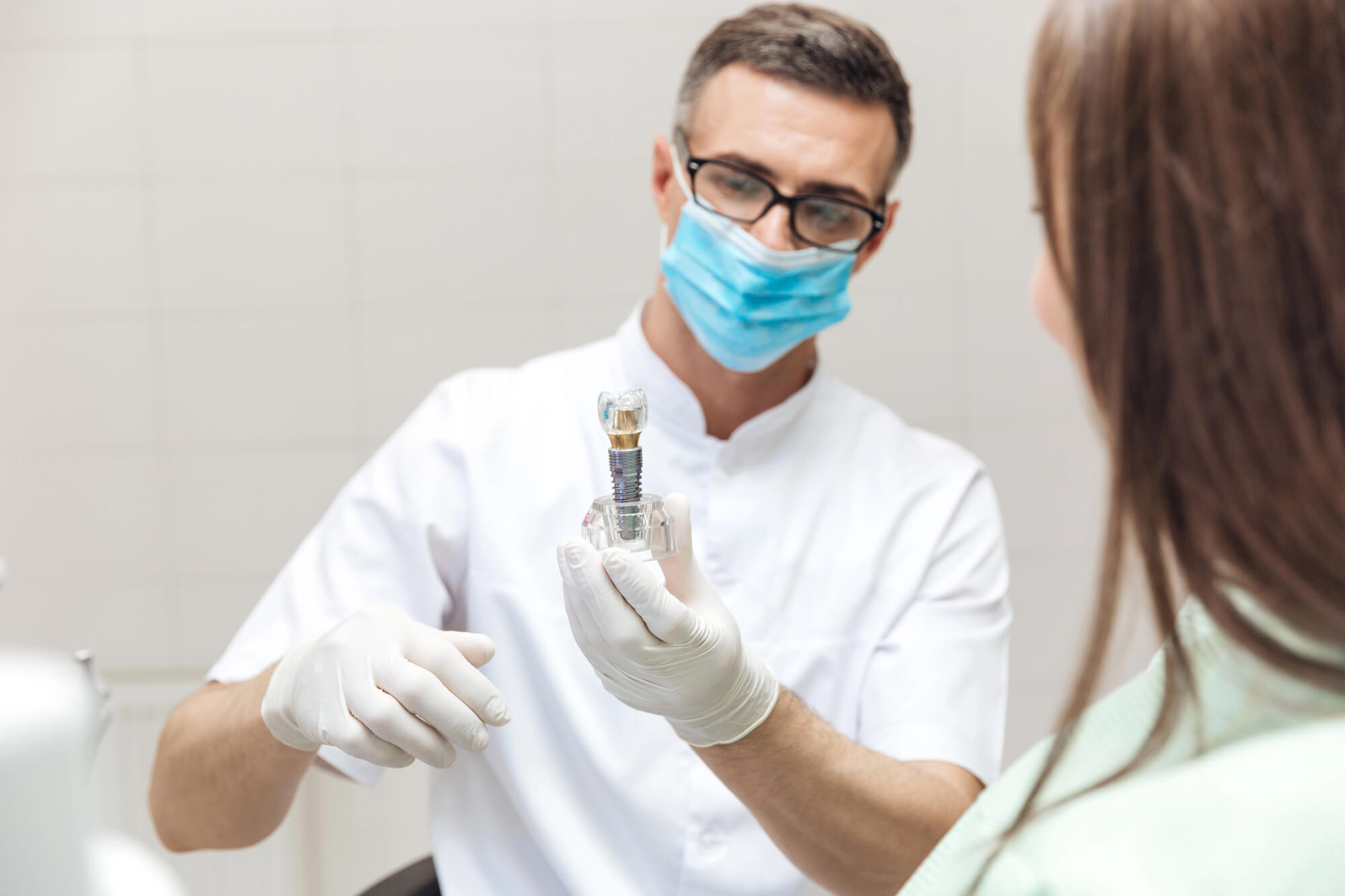 dentist showing patient a model of a single dental implant norfolk va