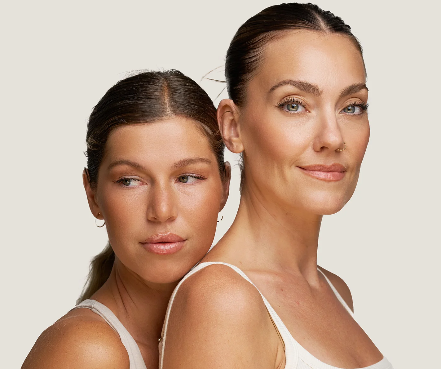 Two young women with youthful, radiant skin with no visible fine lines or wrinkles. 
