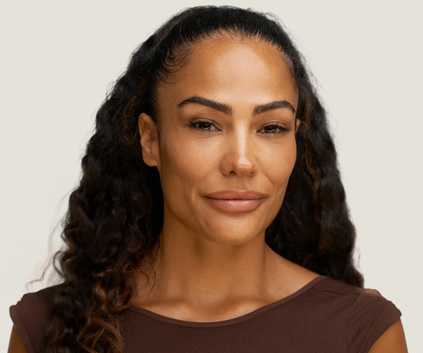 Young woman with rejuvenated skin and bright under-eyes that bring warmth to her face. 