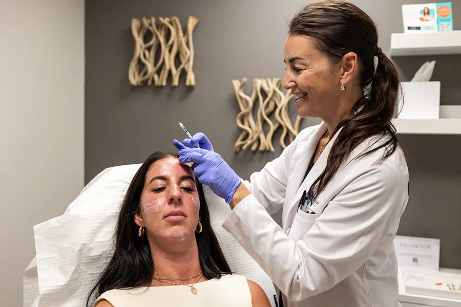 Young woman receiving Dysport injectable treatment in her cheeks, chin, and forehead. 