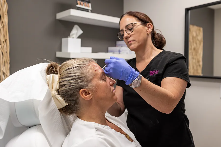Middle-aged woman patient receiving Xeomin injectable treatment in her forehead. 