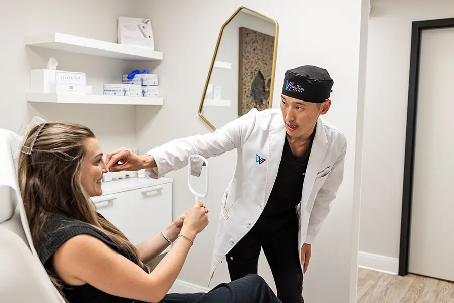 Young woman patient admiring her Radiesse treatment results. 