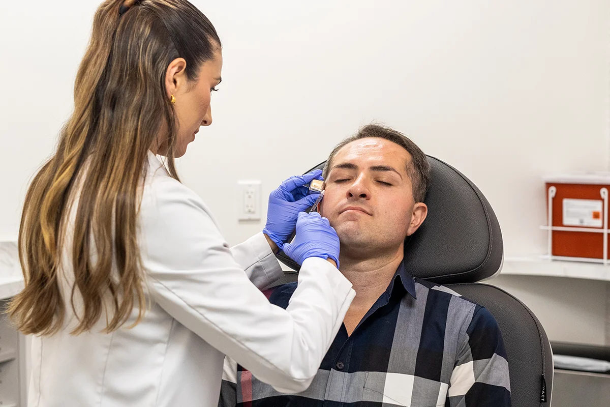 Middle-aged man receiving injectable Dysport treatment in his periorbital area, treating 'crow's feet' lines. 