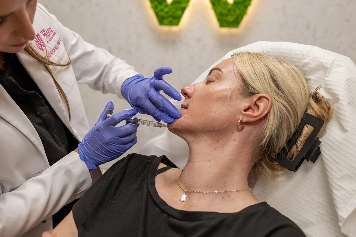 Middle-aged woman receiving injectable dermal filler in her chin for contour enhancement. 