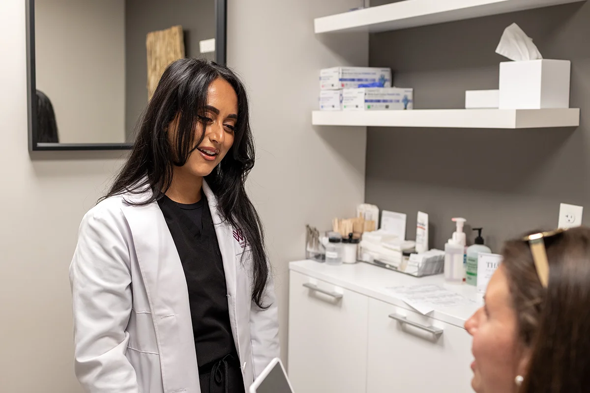 Young woman receiving a consultation from provider Seema Teymouri. 