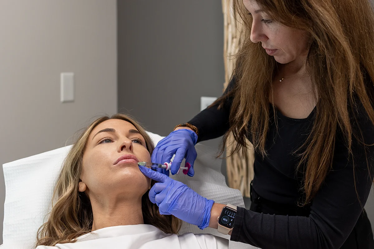 Young woman receiving injectable lip filler in her lips for balanced volume. 
