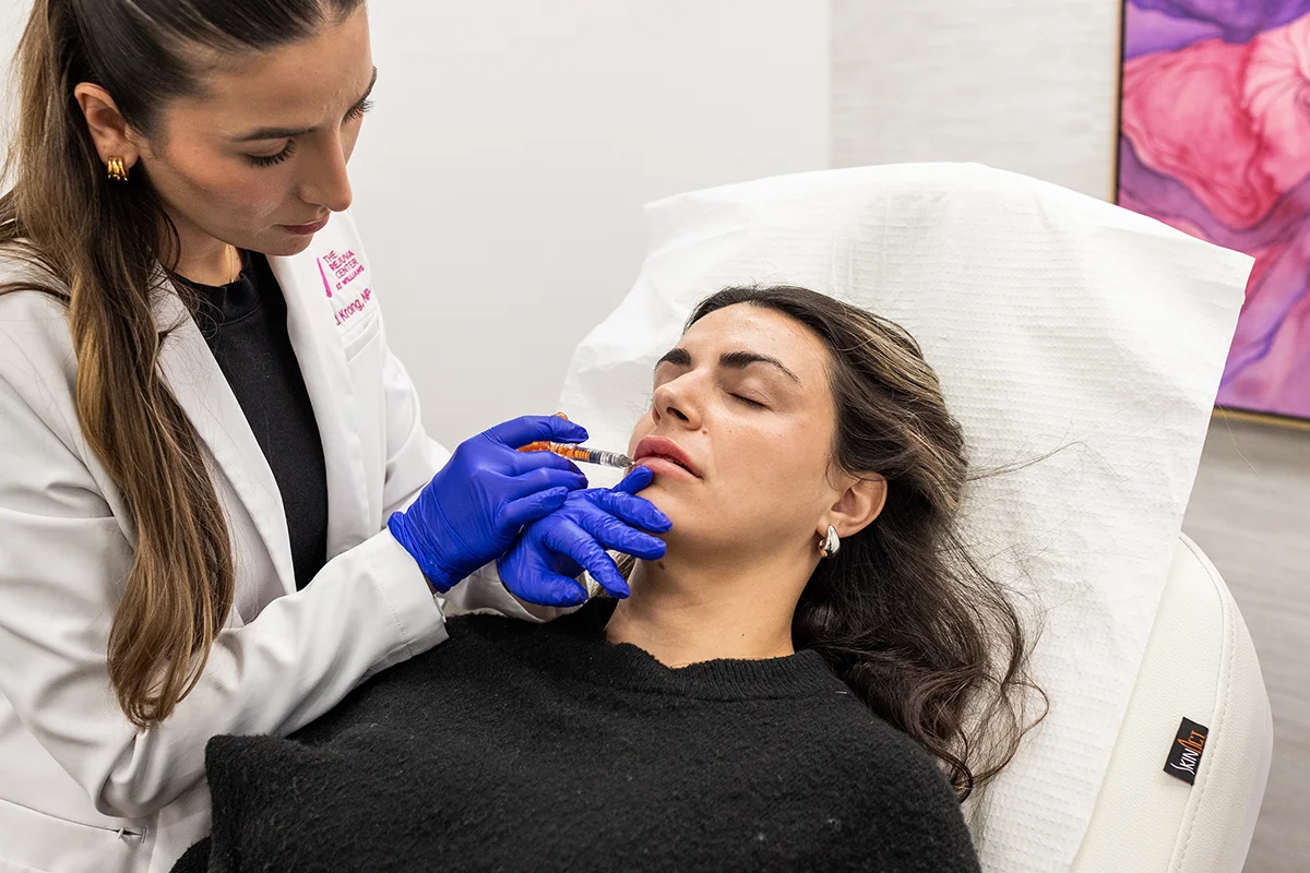 Young woman receiving injectable lip filler in her lips for volume enhancement. 