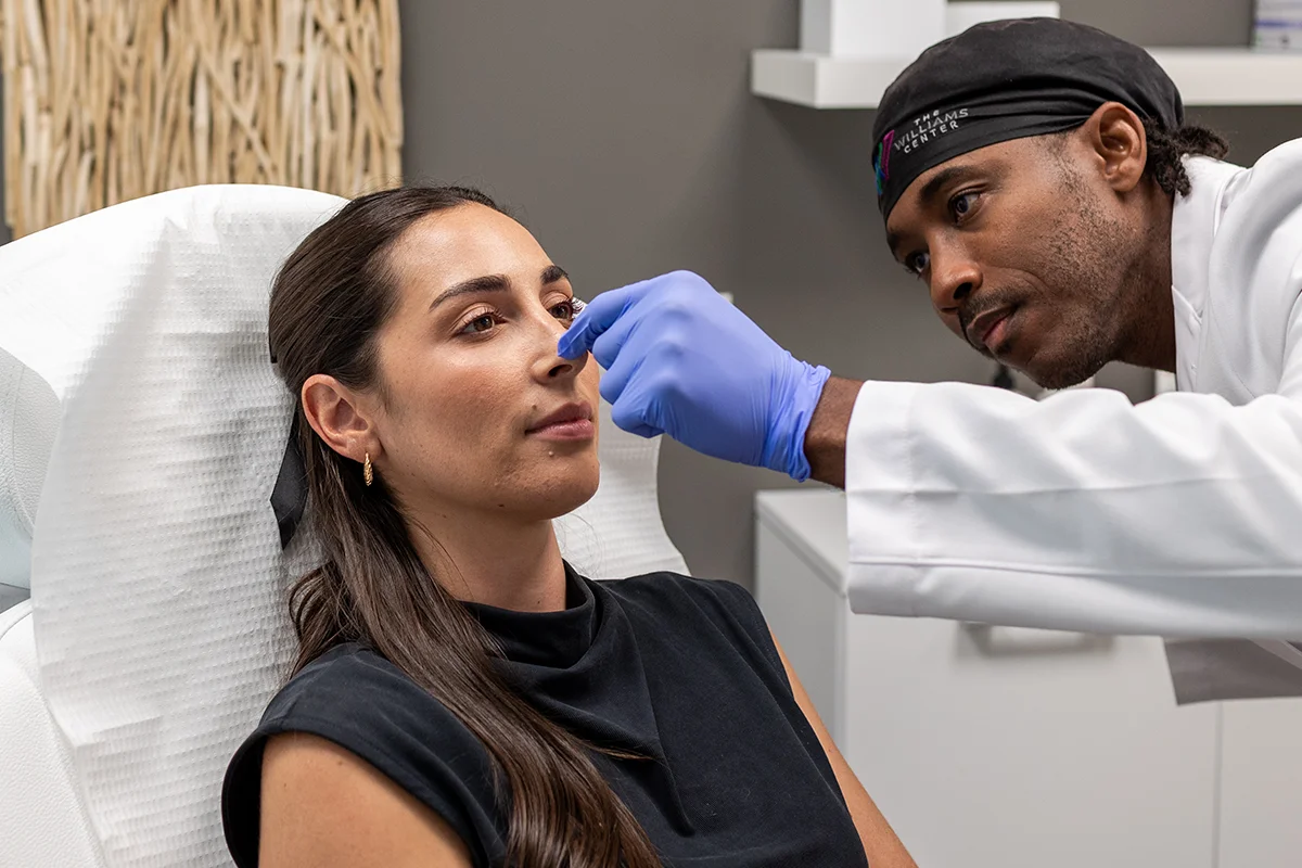 Young woman receiving liquid rhinoplasty injections in her nasal sidewall. 