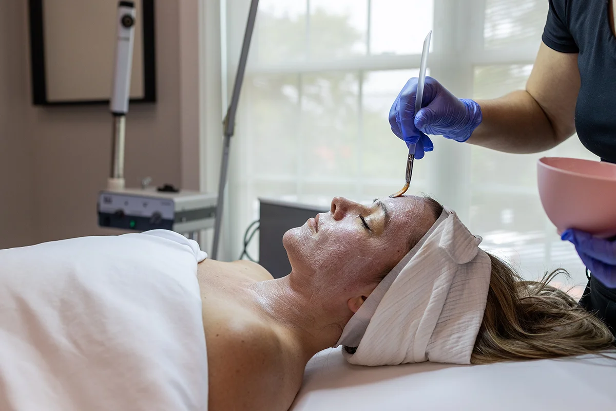 Young woman receiving a chemical peel treatment on her face and neck. 