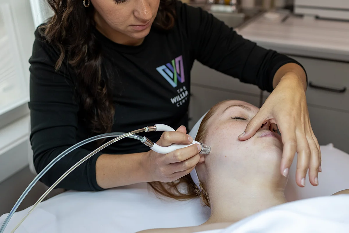 Young woman receiving DiamondGlow facial treatment on her face, near her jawline. 