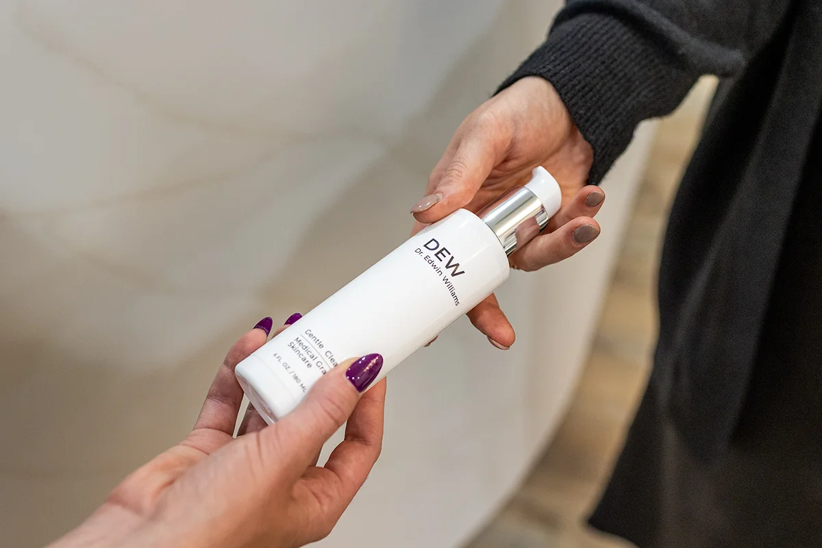 Provider handing a patient the DEW Gentle Cleanser by Dr. Williams, a medical-grade skincare product. 